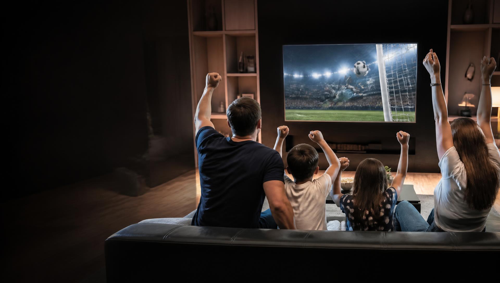 A family celebrating together while watching sport on television at home